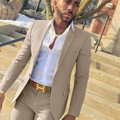 A man wears a slim-fit beige two-piece suit with a white button-down shirt and a tan belt.