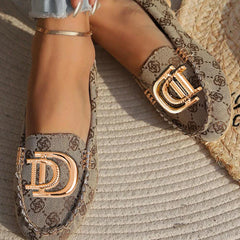 Women's beige patterned loafers featuring a gold-tone D-shaped metal accent on the front.