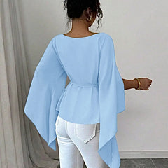 A woman wears a light blue long-sleeve shirt with a slash neck and a belted waist.