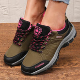 A pair of olive green women's hiking sneakers with black accents, pink trim, and lace-up closures.