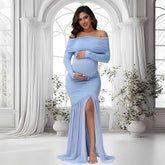 A pregnant woman wears a light blue off-shoulder maternity gown with long sleeves and a front slit.