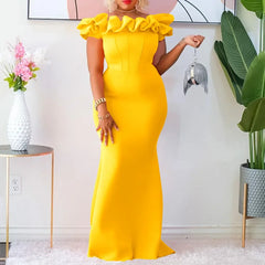 A woman wears a floor-length, off-the-shoulder yellow sheath dress with ruffled neckline detail.