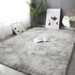 A rectangular, plush gray area rug with a soft, fluffy texture laid on a tiled floor.
