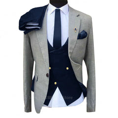 A three-piece men's suit featuring a grey blazer, a navy blue double-breasted vest, and matching pants.