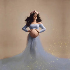 A pregnant woman wears a light blue off-the-shoulder lace top and a long tulle skirt.