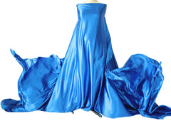A vibrant blue satin fabric draped over a mannequin to create a flowing, wavy effect.