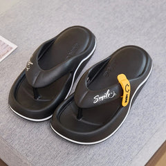 A pair of black platform flip-flops with white trim and a yellow smiley face accent.