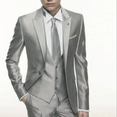 A man wears a slim-fit, three-piece silver grey satin suit with a matching vest and tie.