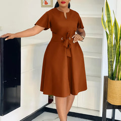 A woman wears a solid brown knee-length A-line dress with short sleeves and a tie-waist belt.