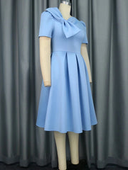 A sky blue knee-length A-line dress featuring short sleeves and a large bow detail at the neckline.