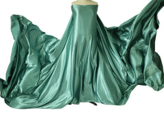 A mannequin displays a long, flowing piece of solid green satin fabric for maternity photography.