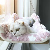 A white Scottish Fold cat rests on a plush, star-patterned hanging window hammock.