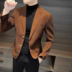 A man wears a brown textured single-breasted blazer over a black turtleneck and trousers.
