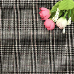 A close-up of fabric featuring a black, white, and tan houndstooth plaid pattern.
