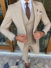 A man wears a beige three-piece slim-fit suit with a peak lapel, brown patterned tie, and vest.
