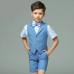 A young boy wears a blue plaid four-piece formal suit consisting of a vest, short-sleeved shirt, shorts, and a bowtie.