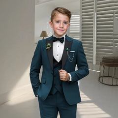 A young boy wears a teal four-piece tuxedo set featuring a peaked lapel blazer and black bow tie.