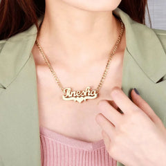 A gold-toned stainless steel nameplate necklace featuring the name Tinesha with a heart accent.