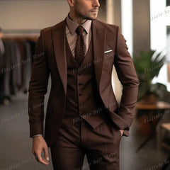 A man wears a dark brown three-piece suit with a matching vest and a patterned tie.