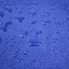 A close-up view of a blue, water-repellent polyester fabric covered in droplets of water.