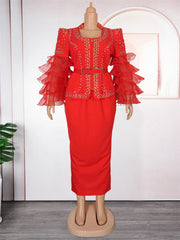 A red floor-length dress with beaded embellishments, a belted waist, and tiered puff sleeves.