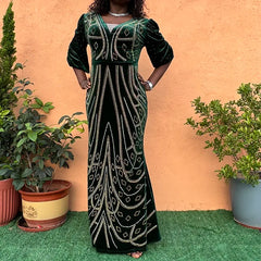 A woman wears a floor-length, dark green velvet evening dress adorned with diamond patterns.