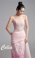 A model wears a sleeveless pink floor-length evening gown with floral embroidery and pleated waist.