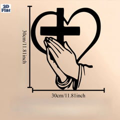 A black metal wall art piece featuring a cross inside a heart with praying hands below.