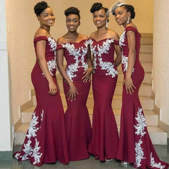 Four women wear matching burgundy off-the-shoulder mermaid bridesmaid dresses with white lace.