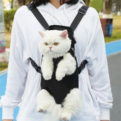 A person wears a black mesh pet carrier backpack containing a fluffy white cat.