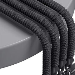 A close-up of four black braided elastic resistance bands attached to a grey fitness device.