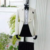 A white jacquard blazer with bead embellishments, wide lapels, and a black bow tie on a mannequin.