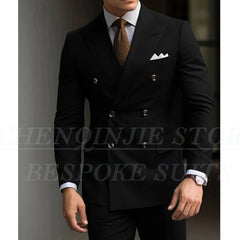 A man wears a black double-breasted slim-fit suit with a light shirt and brown tie.