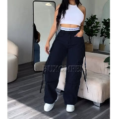 A woman wears loose, high-waisted black cargo jeans with multiple pockets and drawstring details.