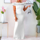 A woman wears a floor-length white off-shoulder sheath dress with ruffled neckline detailing.