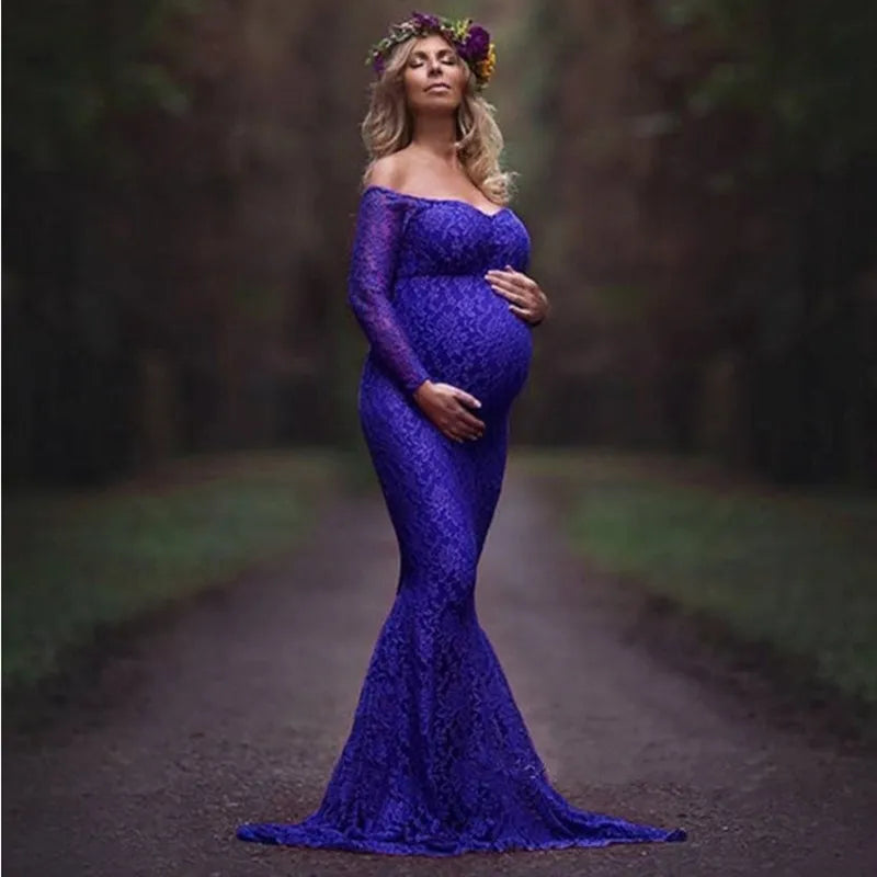 A pregnant woman wears a long-sleeved, off-shoulder royal blue lace mermaid maternity gown.