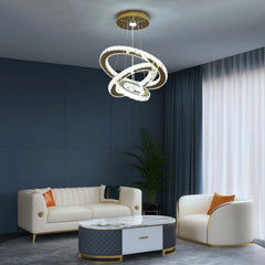 A modern gold and crystal LED chandelier with interlocking rings hangs in a luxury living room.