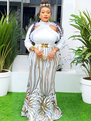 A woman wears a floor-length white and gold sequined African-style gown with puff sleeves.