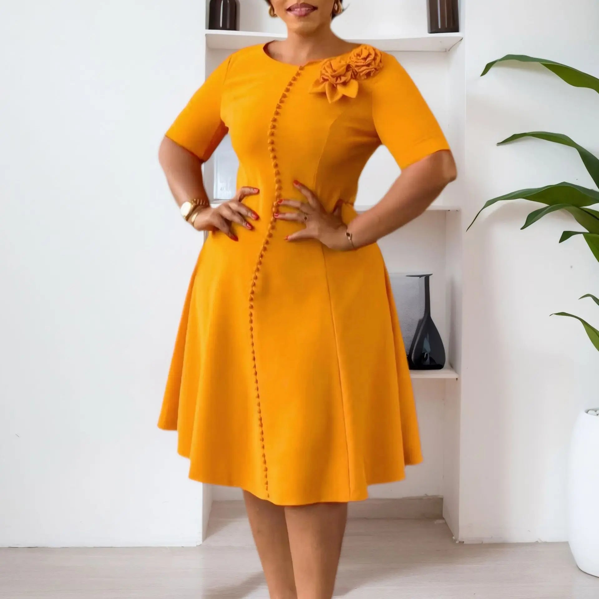 A mustard yellow A-line knee-length dress with short sleeves, a round neckline, and button detail.