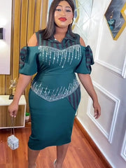 A woman wears a dark green, cold-shoulder midi dress with striped accents and beaded embellishments.