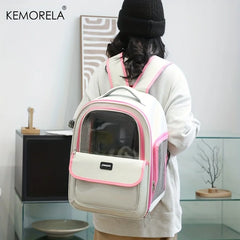 A person wears a white and pink pet carrier backpack with a clear window on their back.