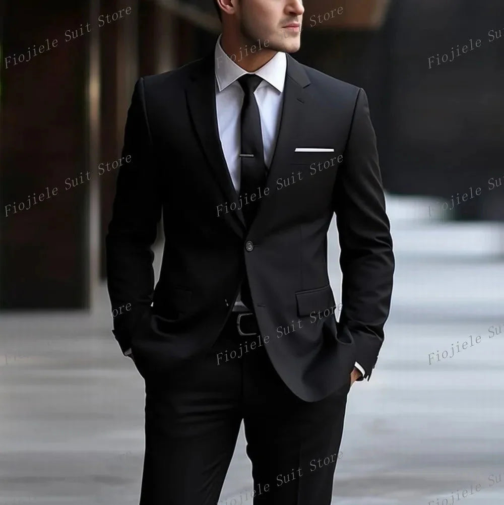 A man wearing a black two-piece formal suit with a white shirt and black tie.