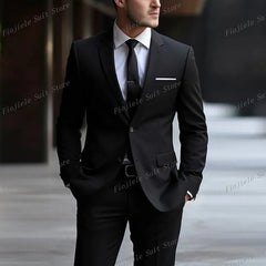 A man wearing a black two-piece formal suit with a white shirt and black tie.