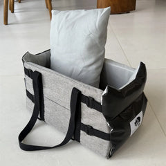 A grey and black portable pet car seat with a soft cushion inside.