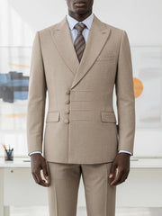 A man wears a tan double-breasted suit with a unique four-button closure and a striped tie.