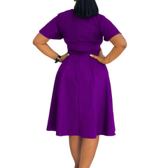 A woman wears a solid purple short-sleeved knee-length A-line swing dress from the back view.