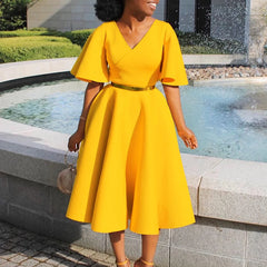 A woman wears a bright yellow V-neck midi dress with butterfly sleeves and a metallic waist belt.