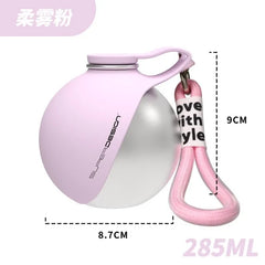 A spherical stainless steel pet water bottle in soft pink with a matching carrying lanyard.