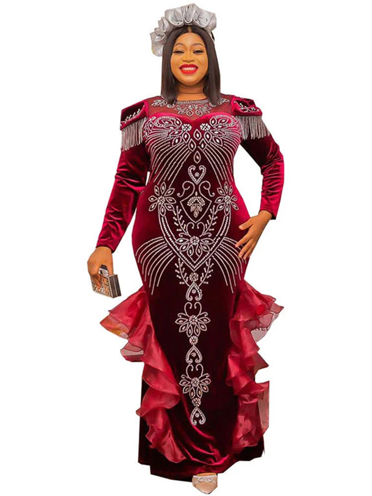 A woman wears a long-sleeved, floor-length burgundy velvet mermaid gown with crystal embellishments.
