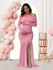 A pregnant woman wears a pink off-shoulder maternity gown with long sleeves and a side slit.